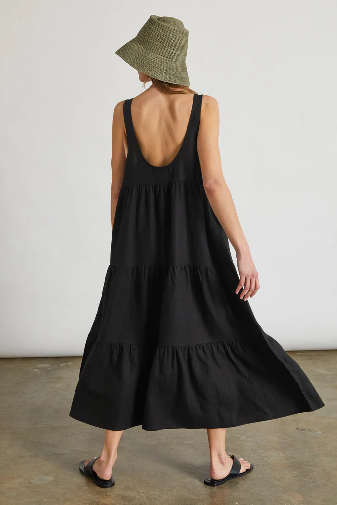 Woman wearing a black sleeveless dress and green bucket hat against a plain background