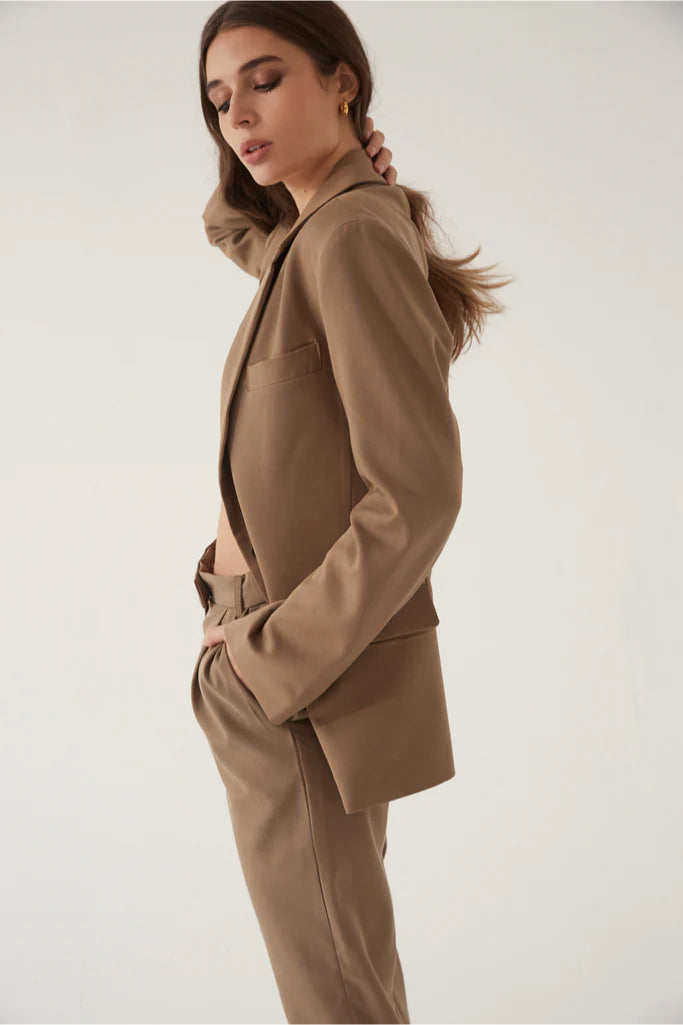Woman wearing a beige suit against a plain background