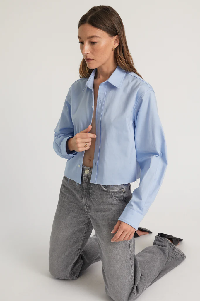 Woman wearing a light blue shirt and gray pants on a white background