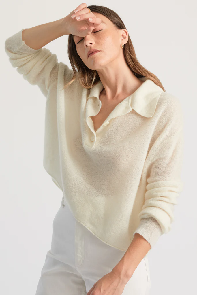 Woman wearing a light-colored sweater with a plain background