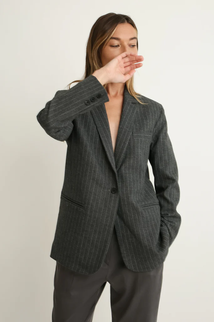 Woman wearing a gray pinstripe blazer on a plain background