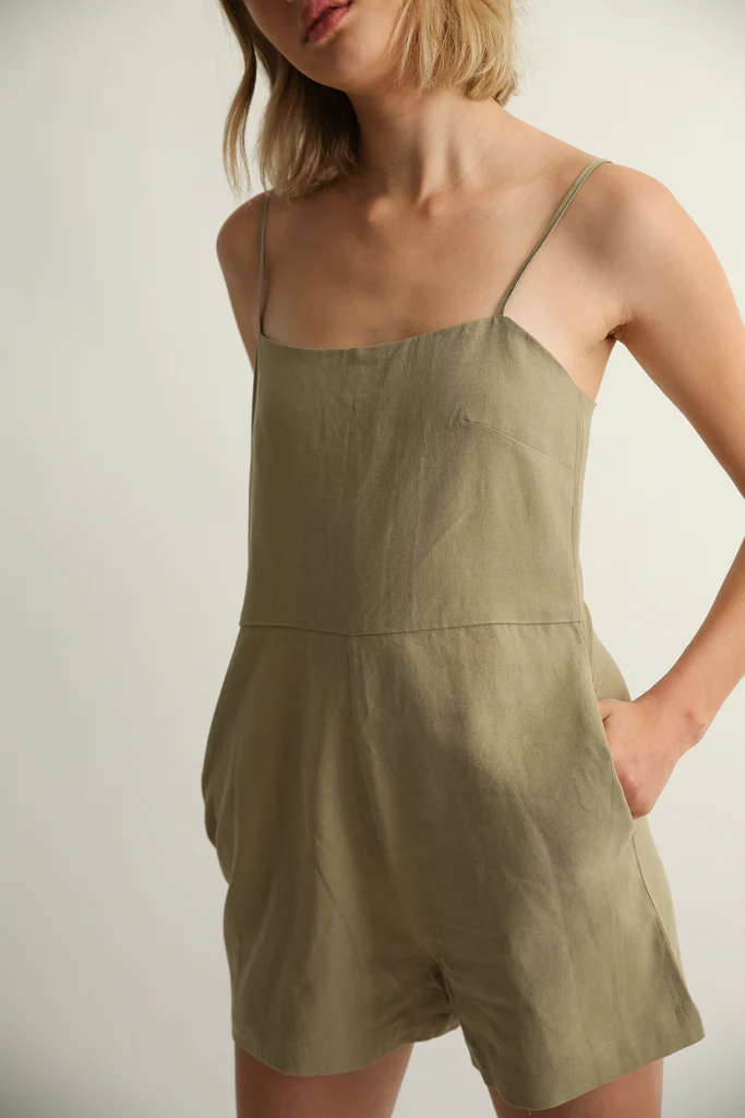 Woman wearing a green romper against a plain background