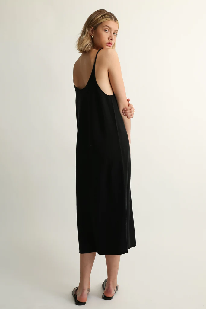 Woman wearing a black slip dress against a white background