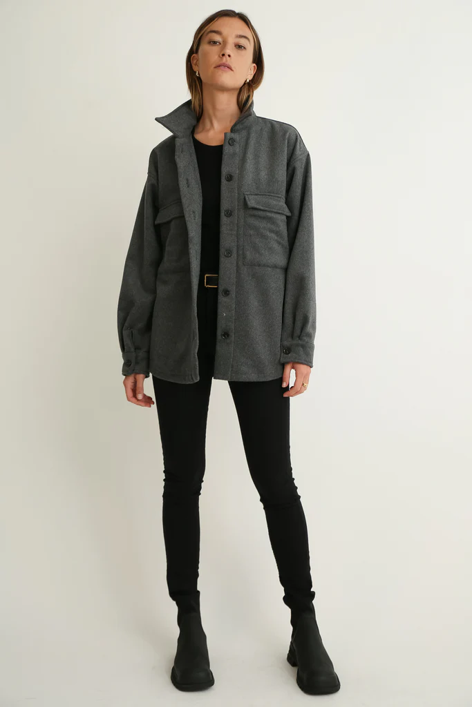 Person wearing a gray wool jacket over a black shirt and pants on a white background