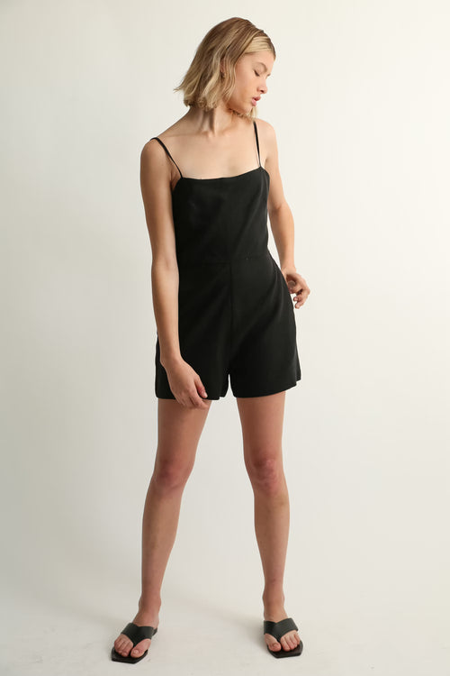 Woman wearing a black romper on a plain background