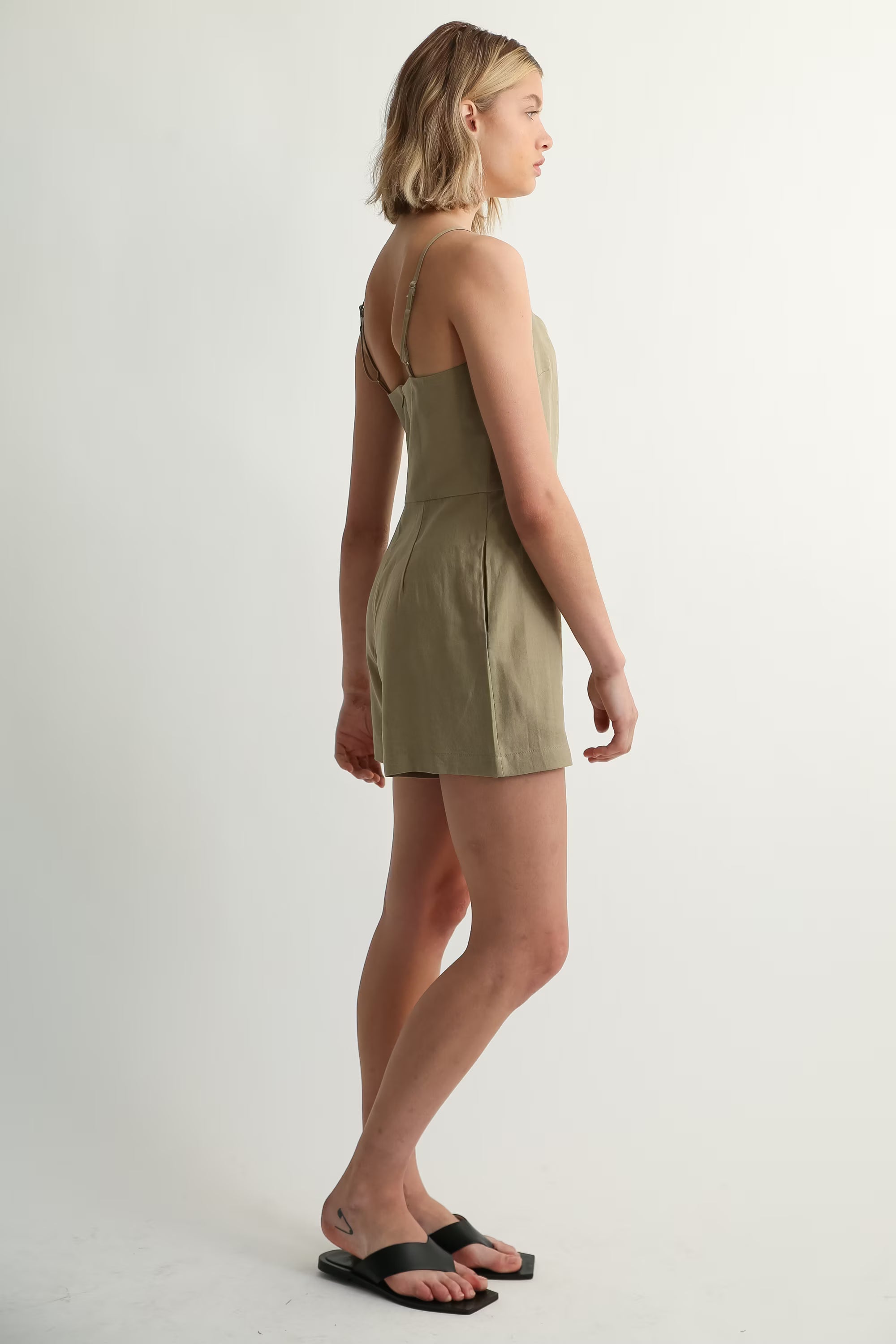 Woman wearing a green romper standing against a white background
