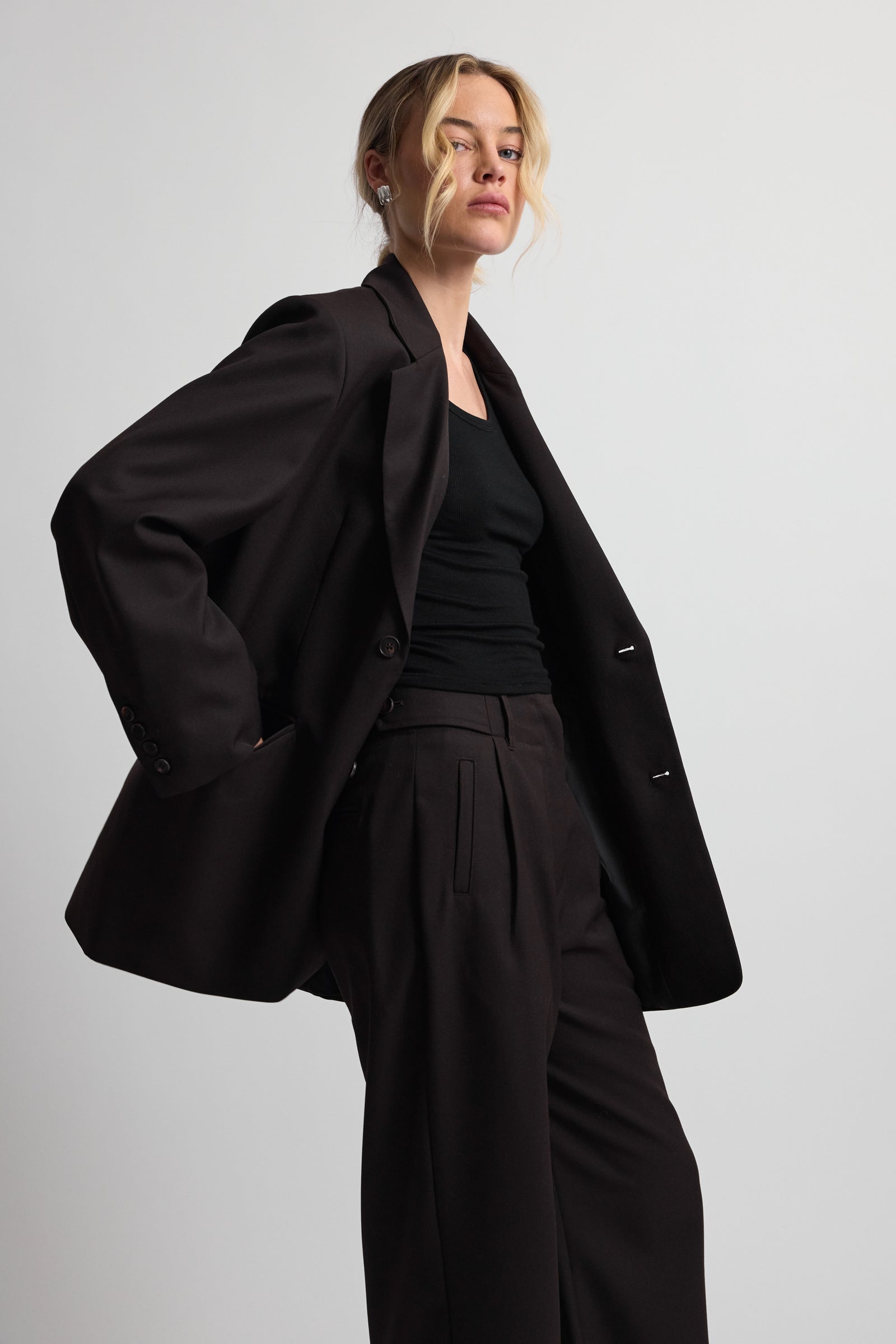 Woman wearing a dark brown suit on a plain background