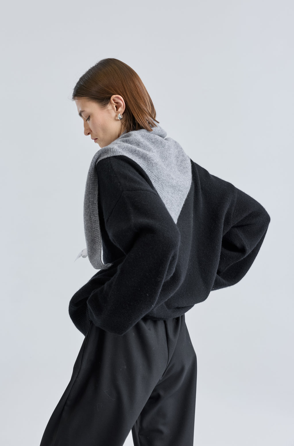 Woman wearing a grey scarf over a black outfit on a light grey background