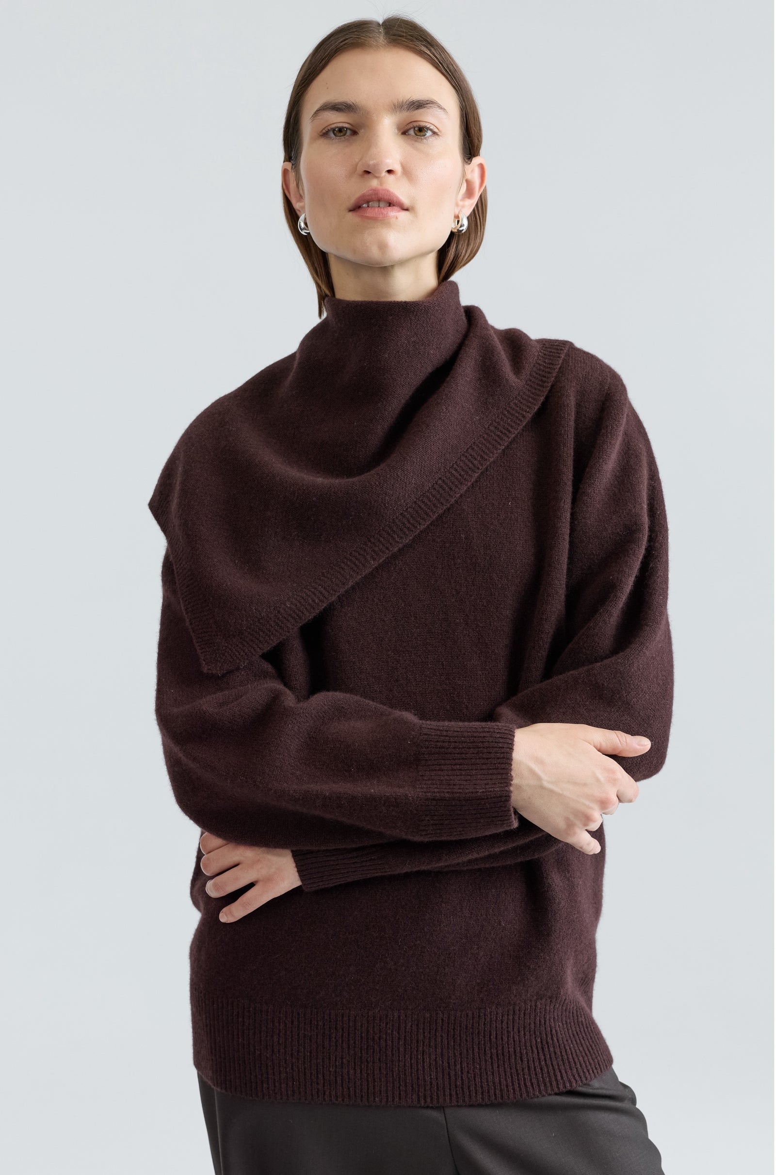 Woman wearing a brown sweater against a light gray background