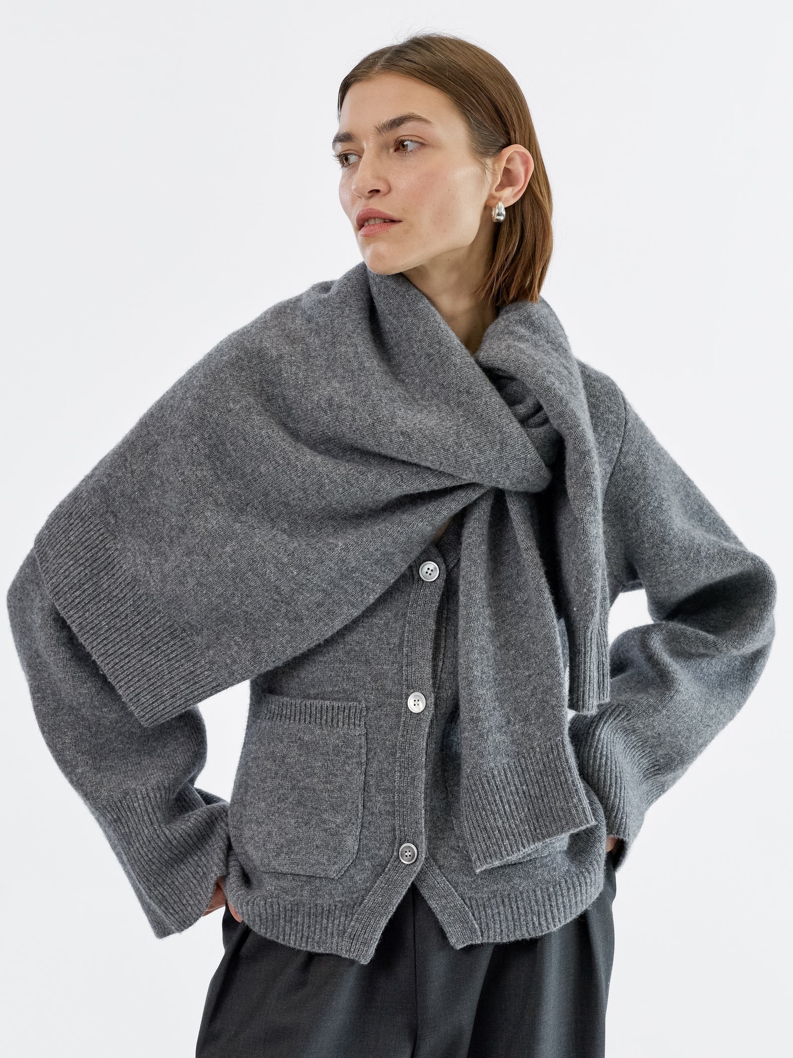 Woman wearing a grey v neck cardigan with a grey wool sweater draped over her shoulders