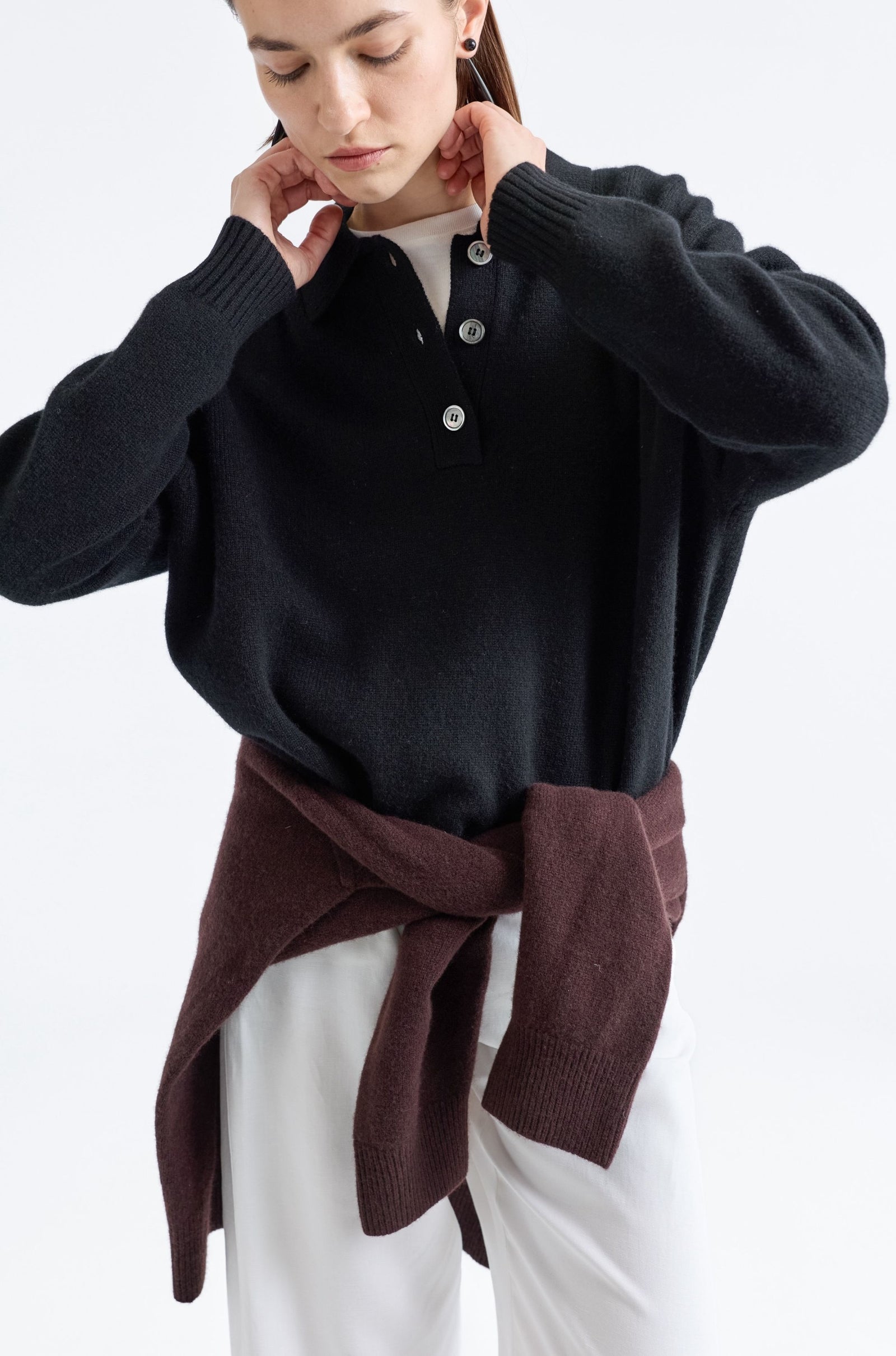 Person wearing a black sweater with a brown accent on a white background