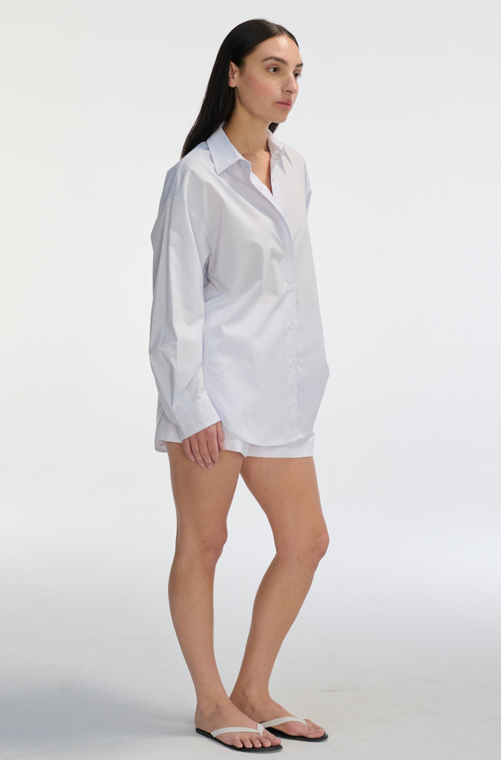 Woman wearing a white and pink stripe sheer shirt and shorts on a white background