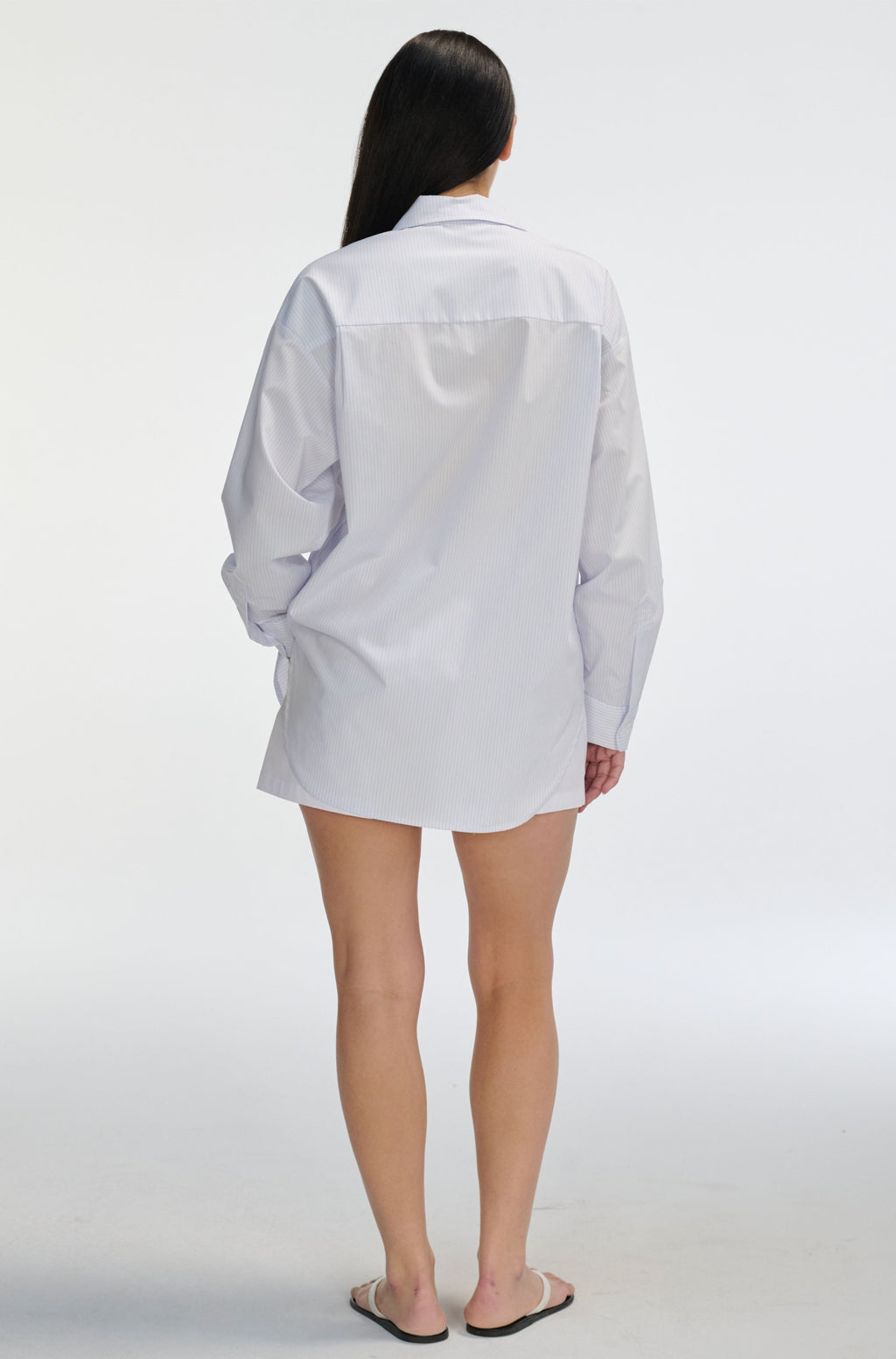 Person wearing a white and pink stripe shirt on a plain background