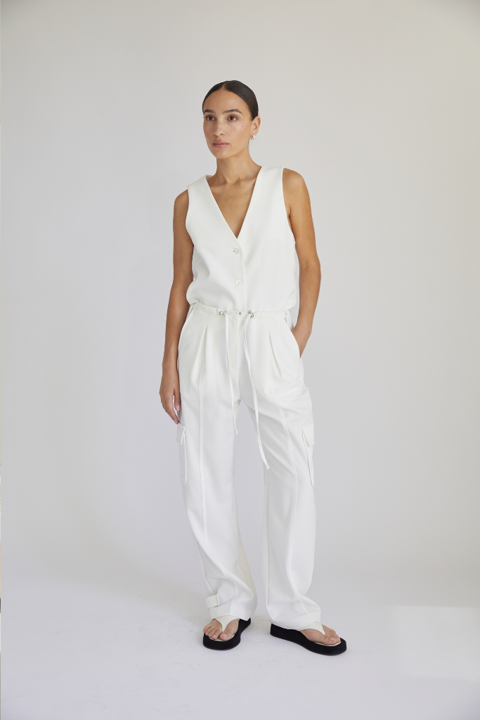 Woman wearing a white sleeveless jumpsuit on a plain background