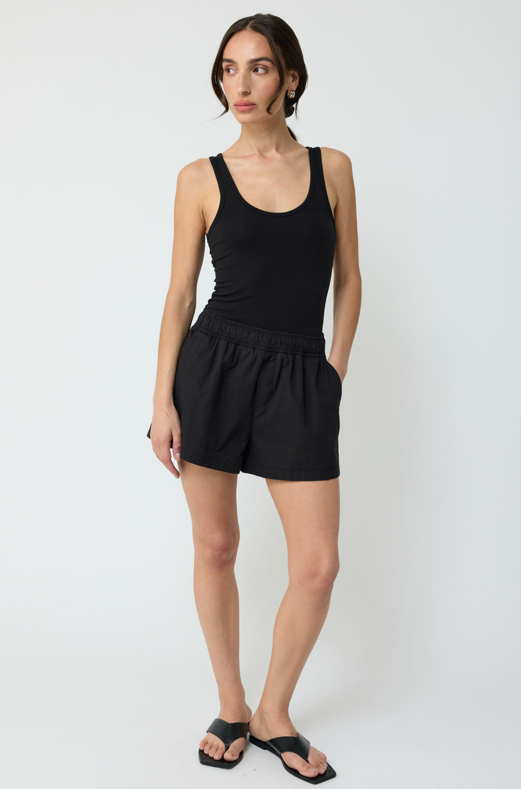 Woman wearing a black tank top and shorts on a white background