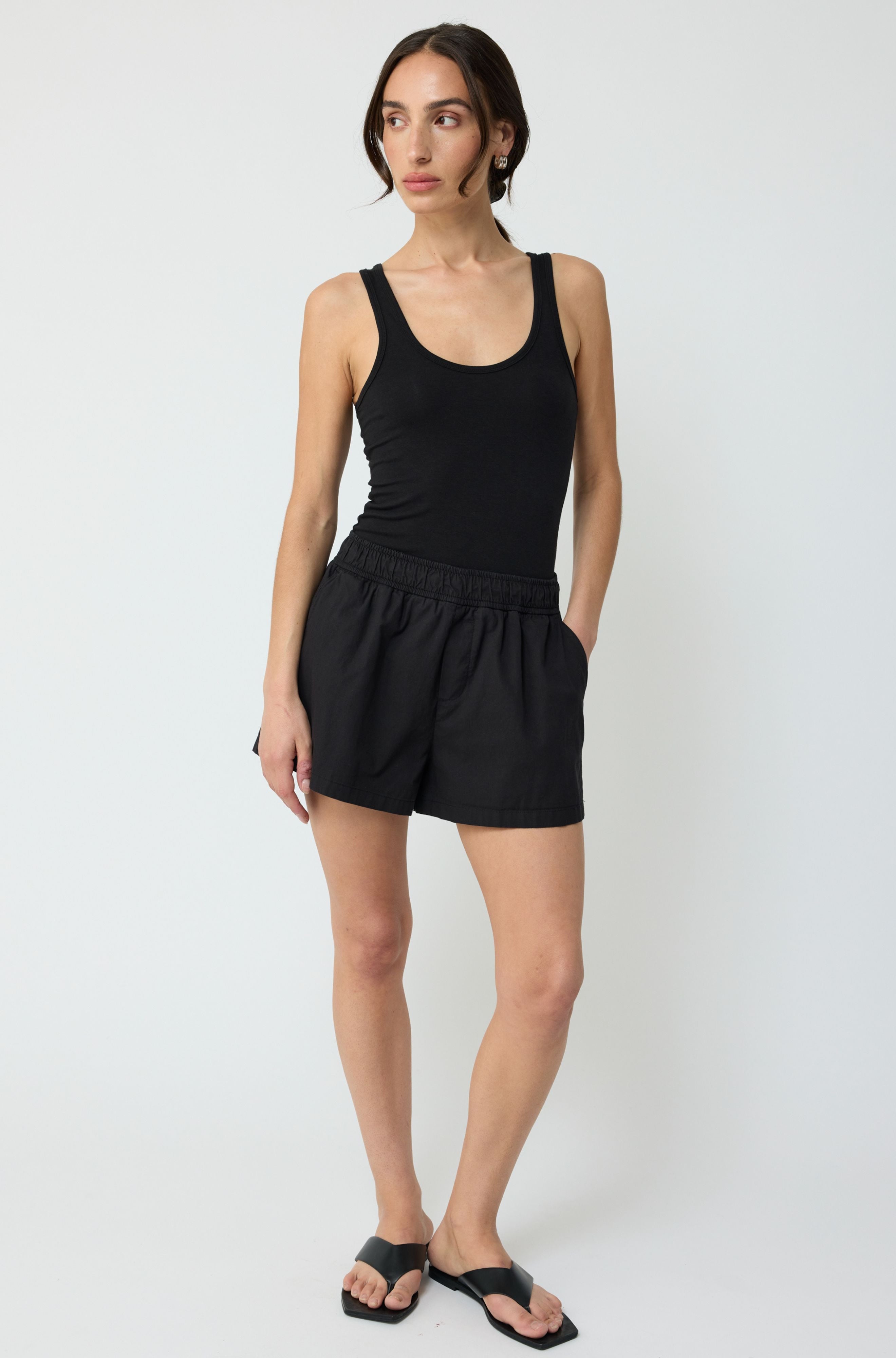 Woman wearing a black tank top and shorts on a white background