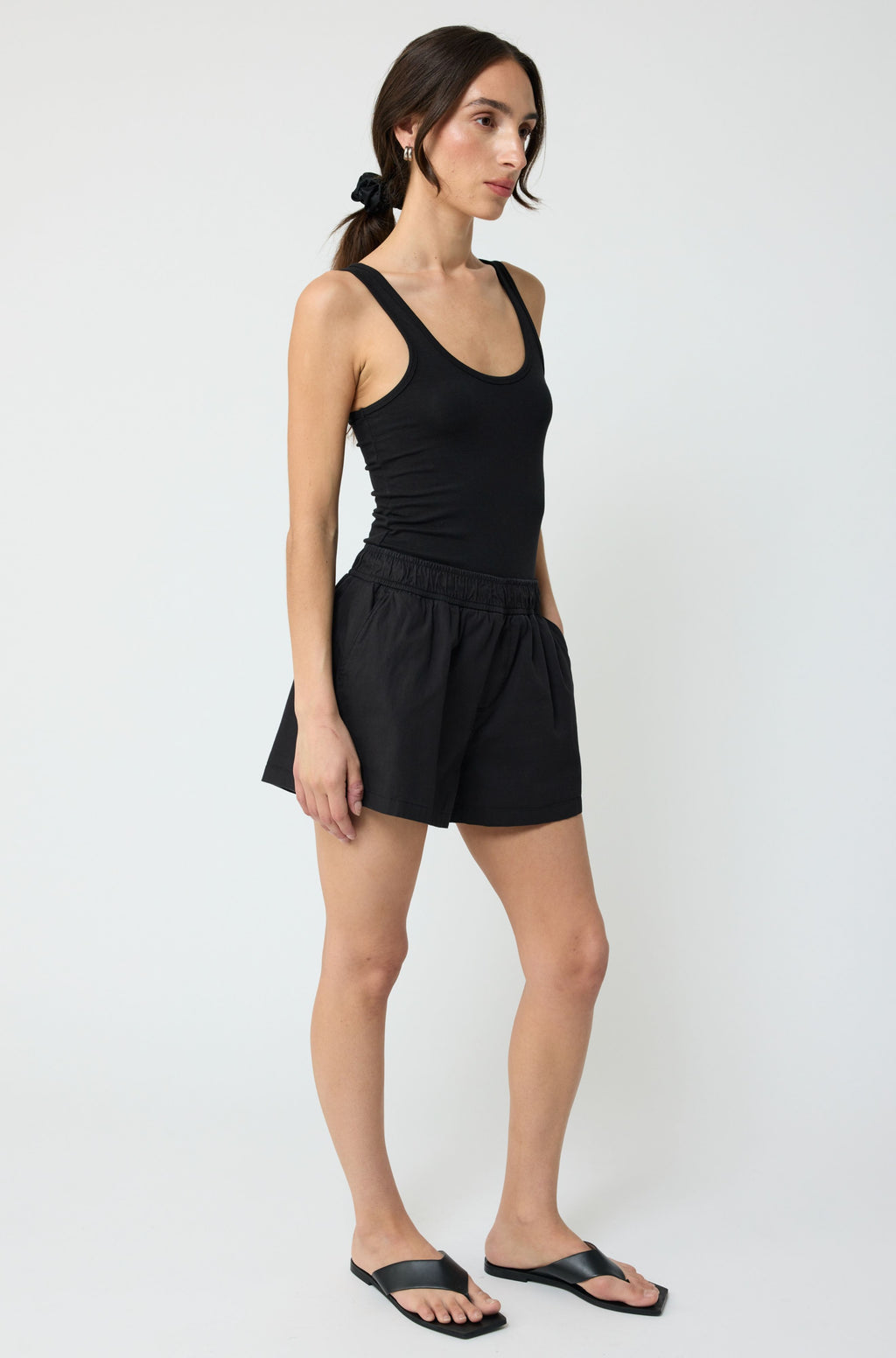 Woman wearing a black tank top and shorts on a white background