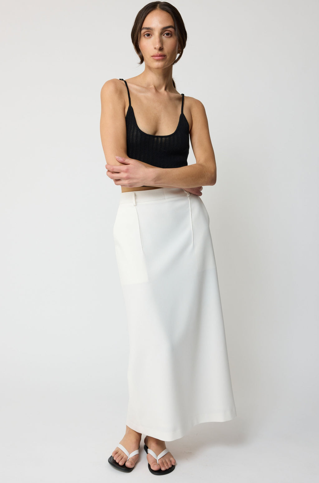 Woman wearing a black top and white skirt on a white background