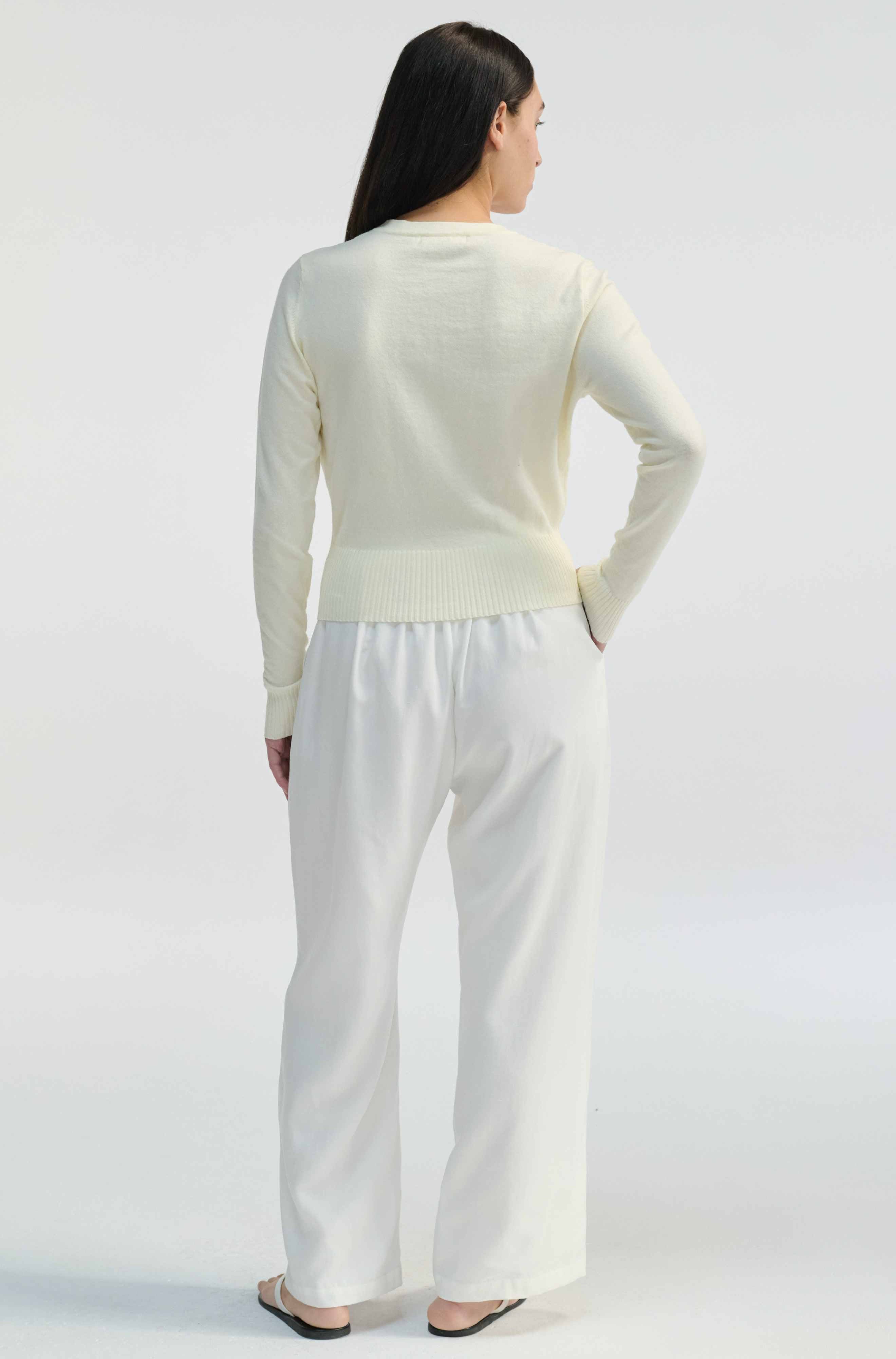 Woman wearing a white outfit on a plain background