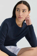 Woman wearing a navy blue sweater and white shorts against a light background
