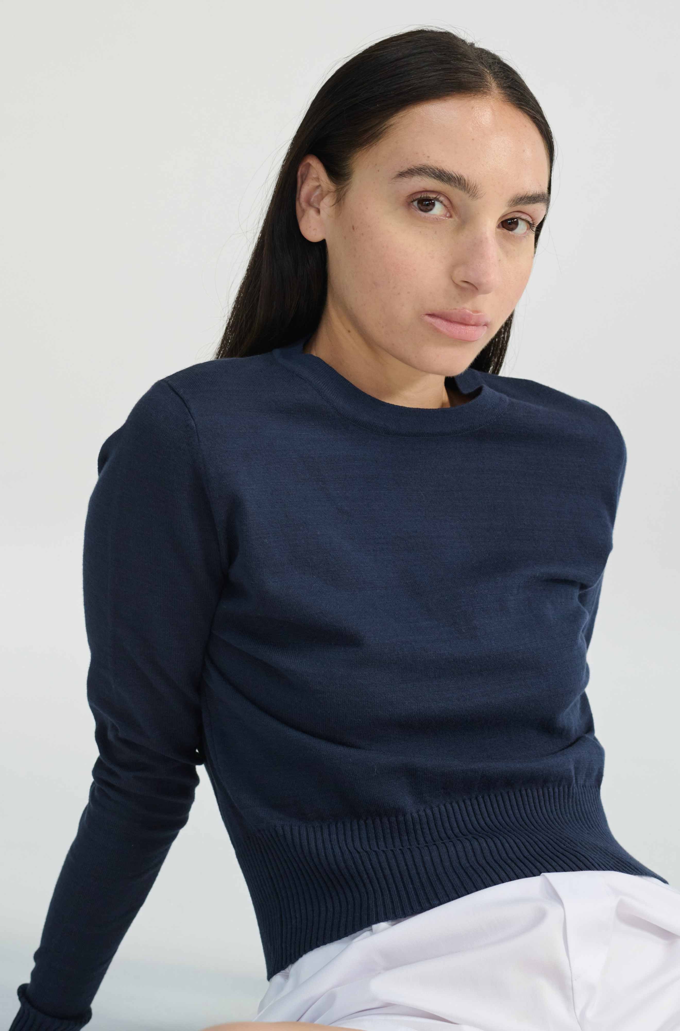 Person wearing a navy blue sweater against a white background