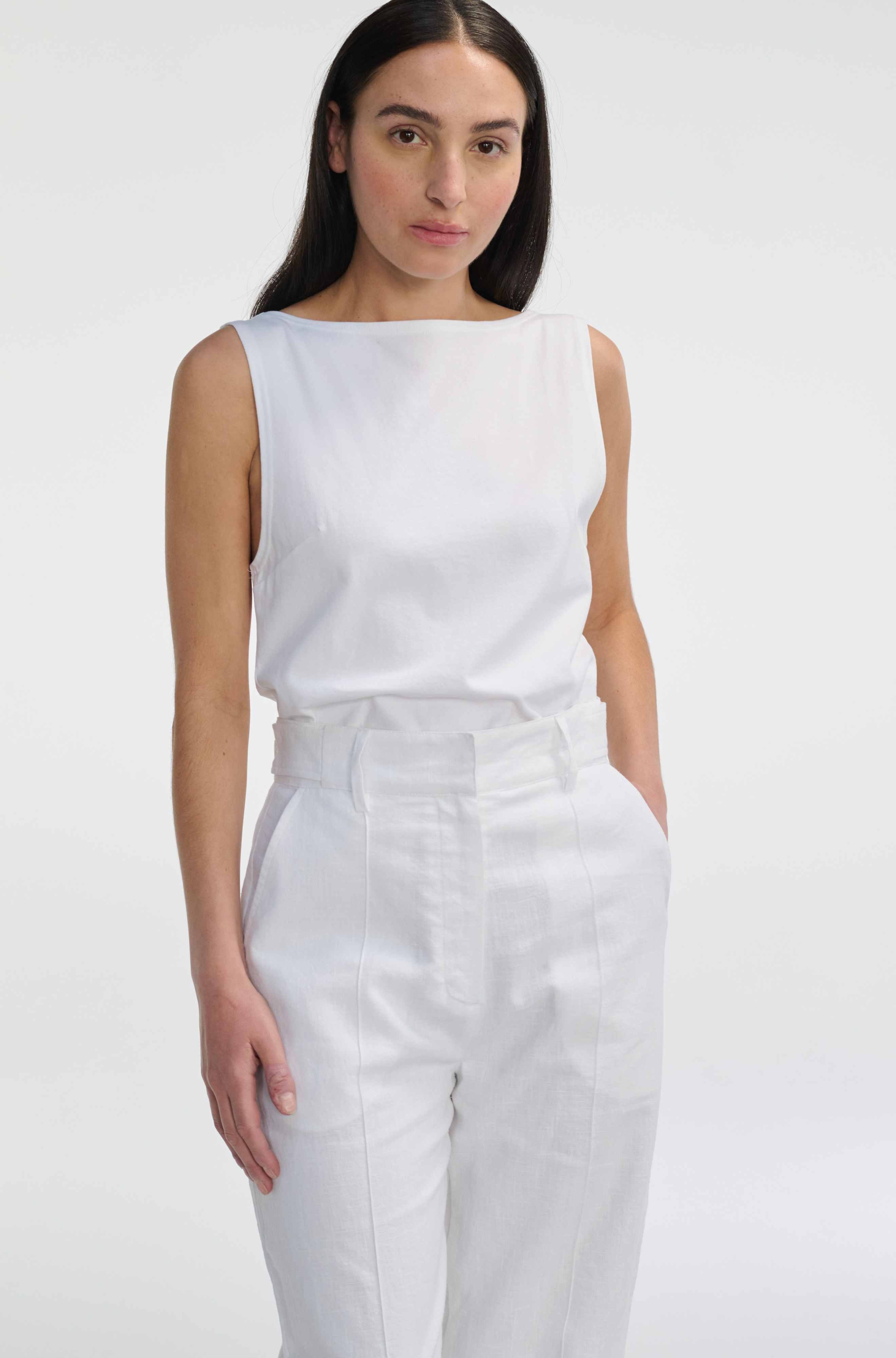 Woman wearing a white sleeveless top and pants on a white background
