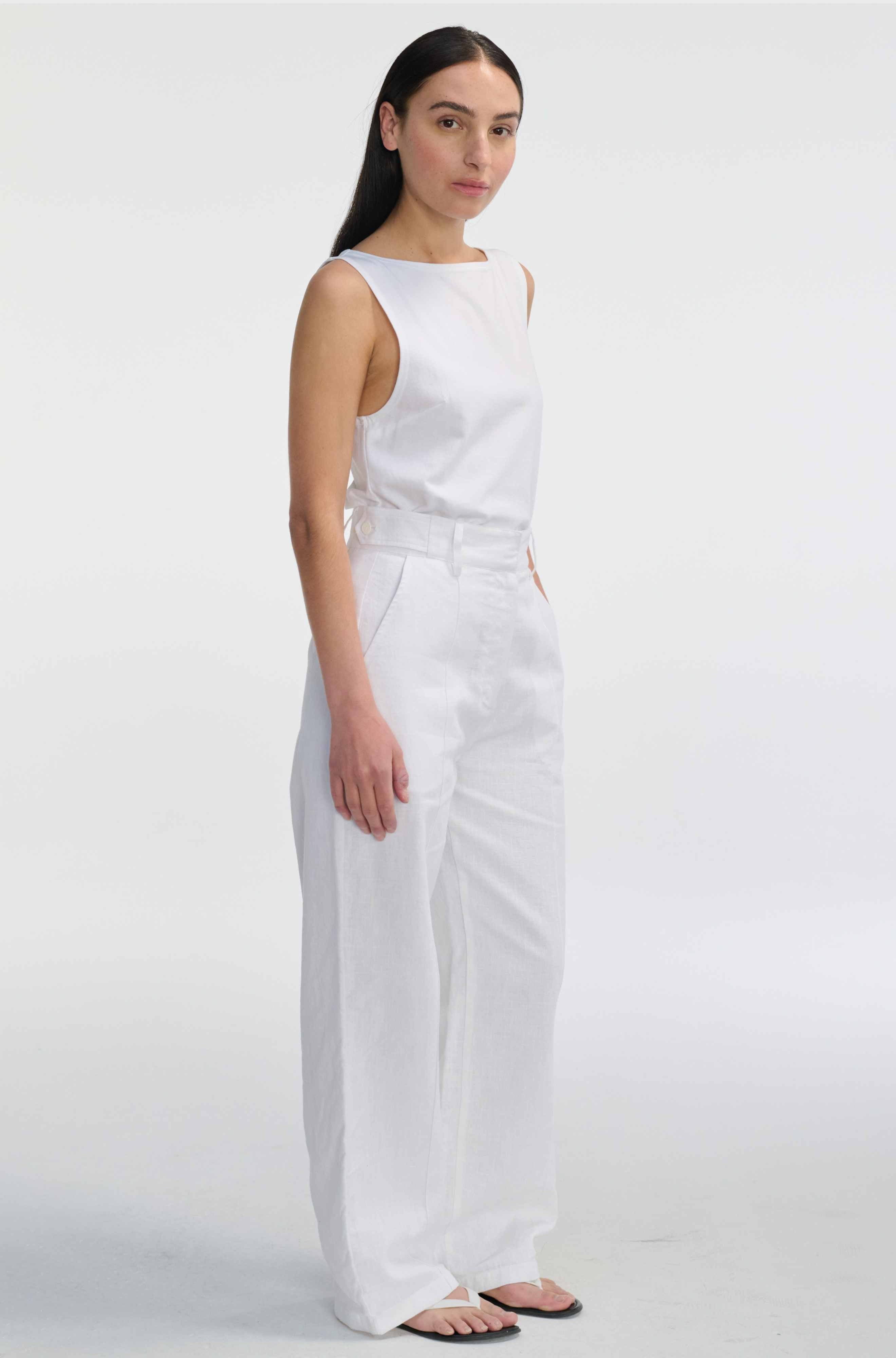 Woman wearing a white sleeveless top and pants on a white background