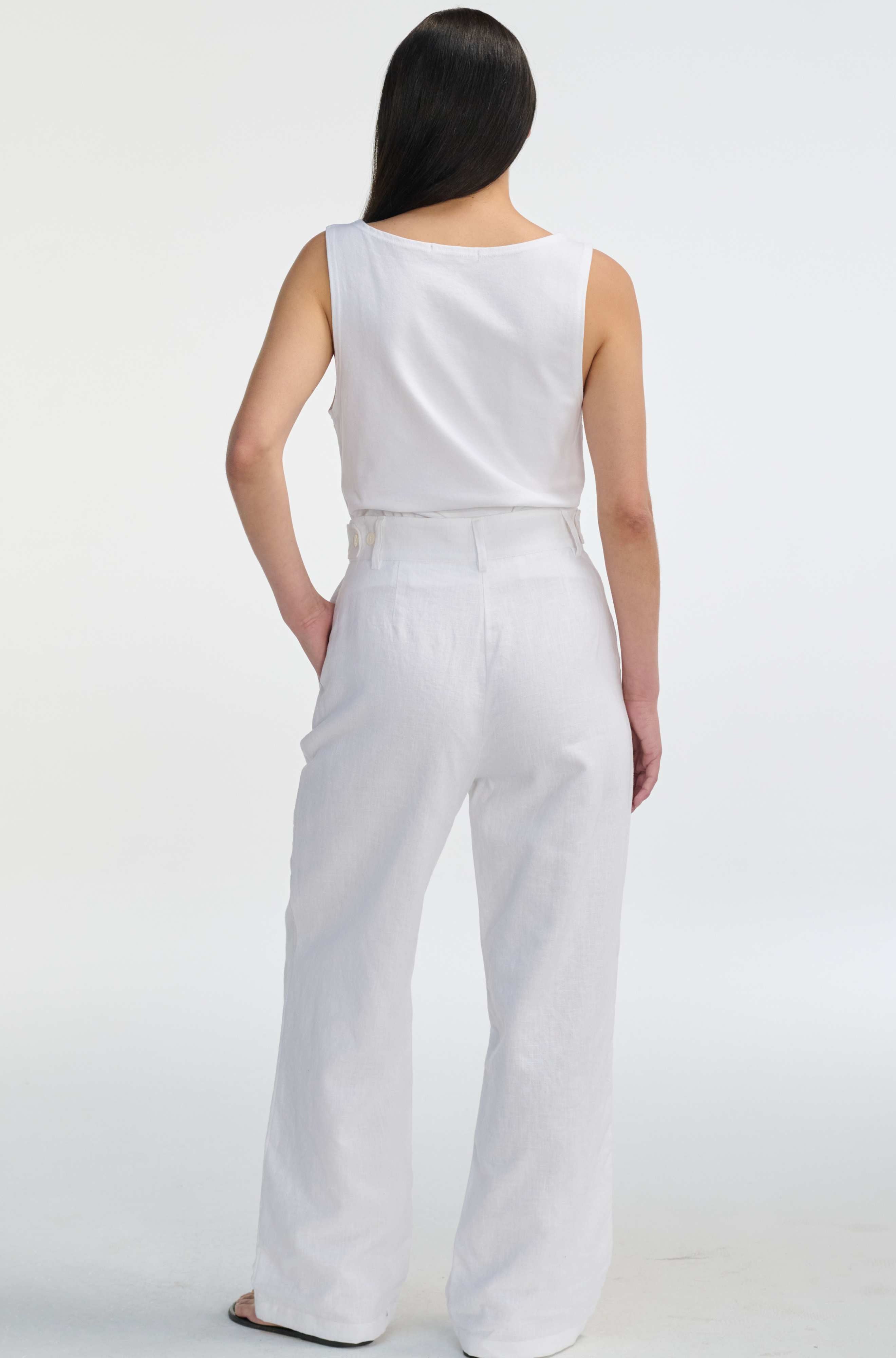 Woman wearing a white sleeveless top and wide-leg pants on a white background