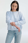 Woman wearing a light blue sweatshirt and jeans on a white background