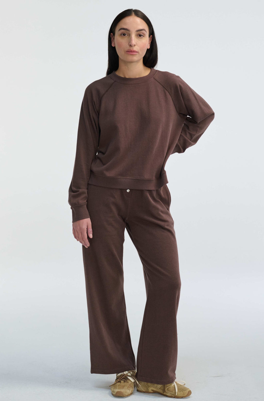 Woman wearing a brown sweatshirt and pants on a white background