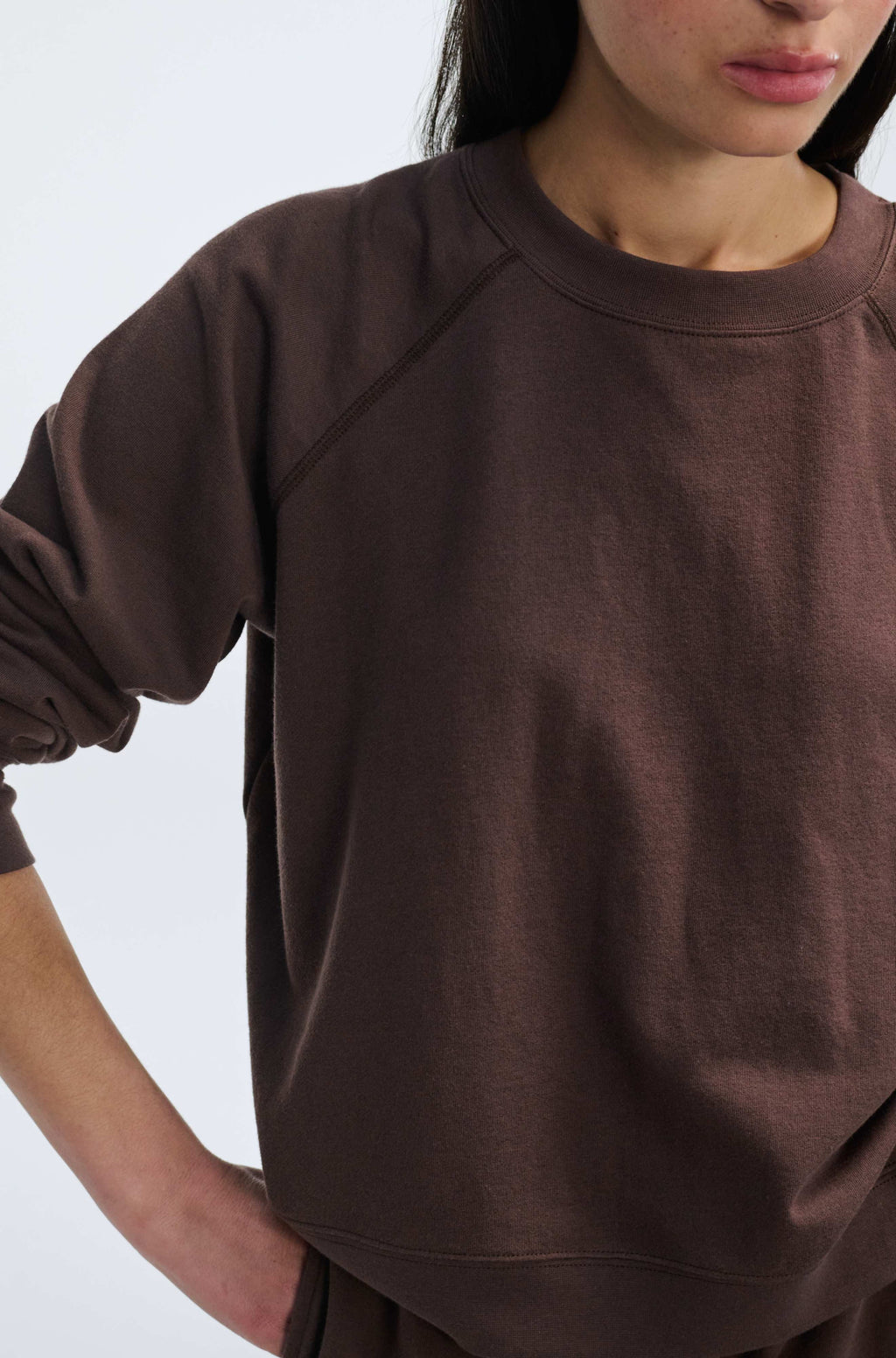 Person wearing a brown sweatshirt against a white background