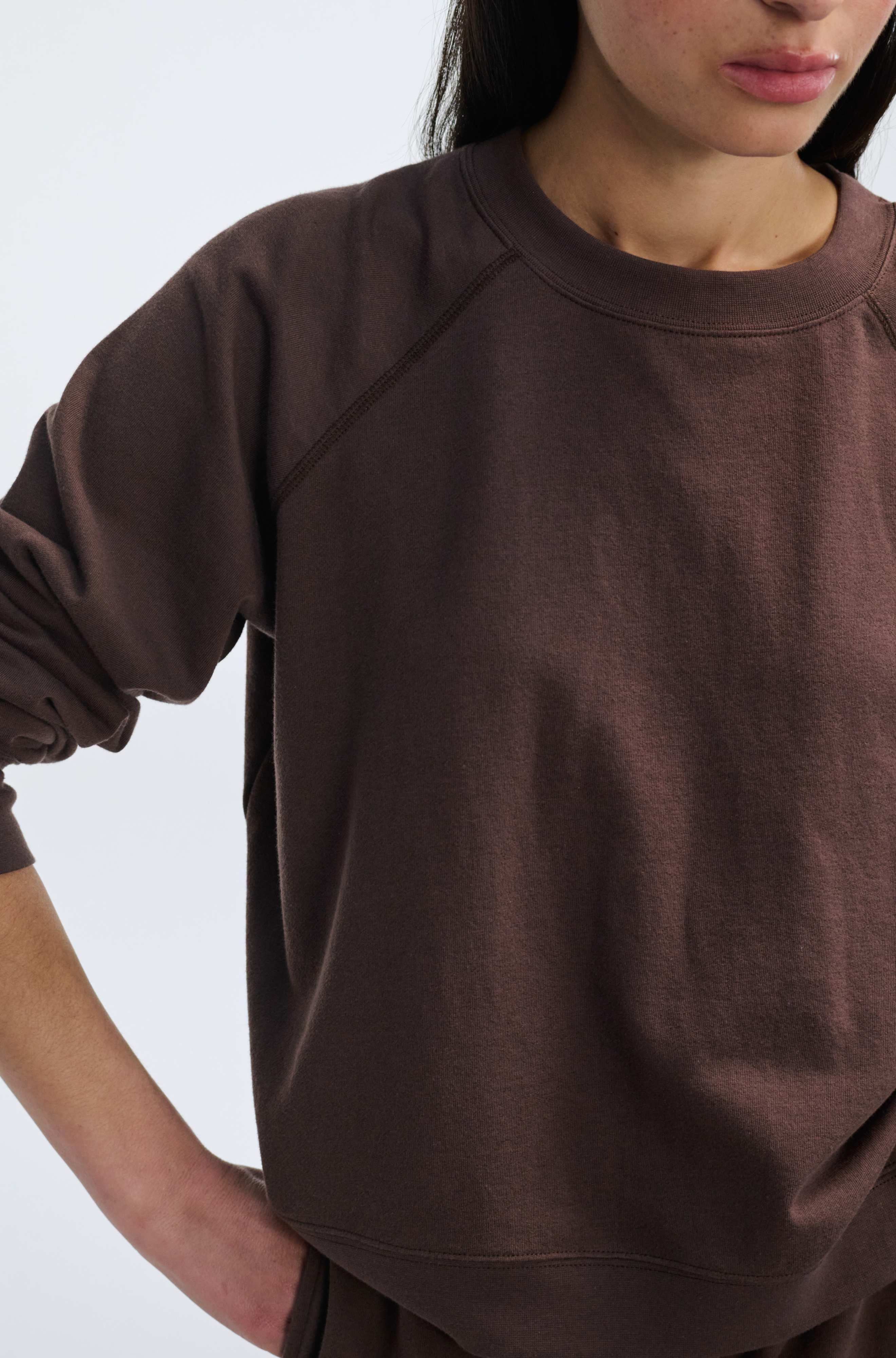 Person wearing a brown sweatshirt against a white background