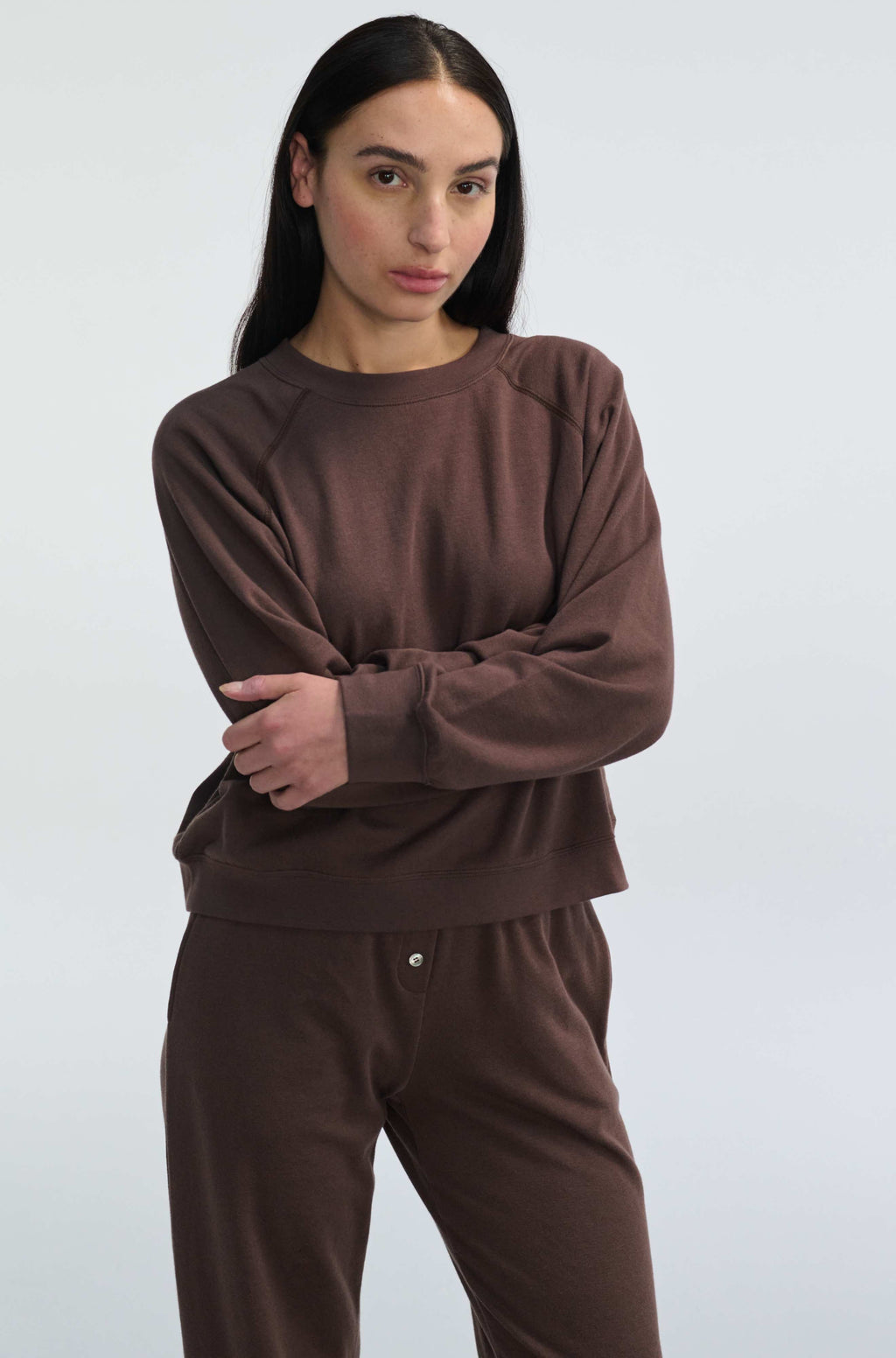 Woman wearing a brown sweatshirt and pants against a white background