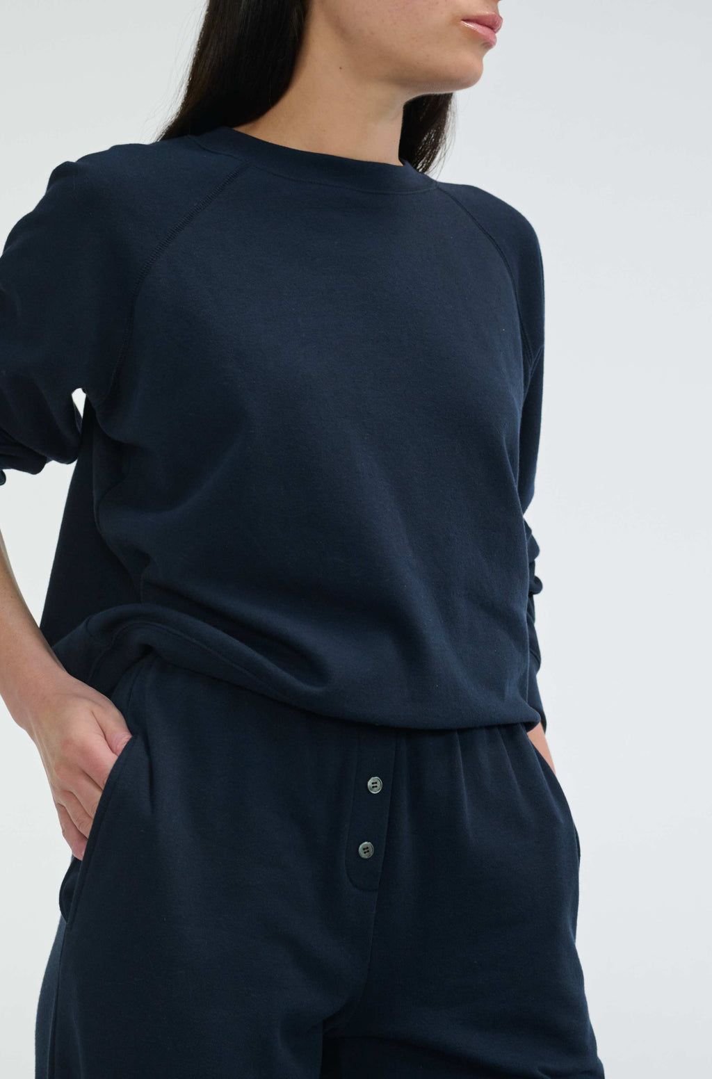 Person wearing a navy blue outfit with a plain background