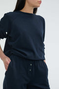 Person wearing a navy blue outfit with a plain background