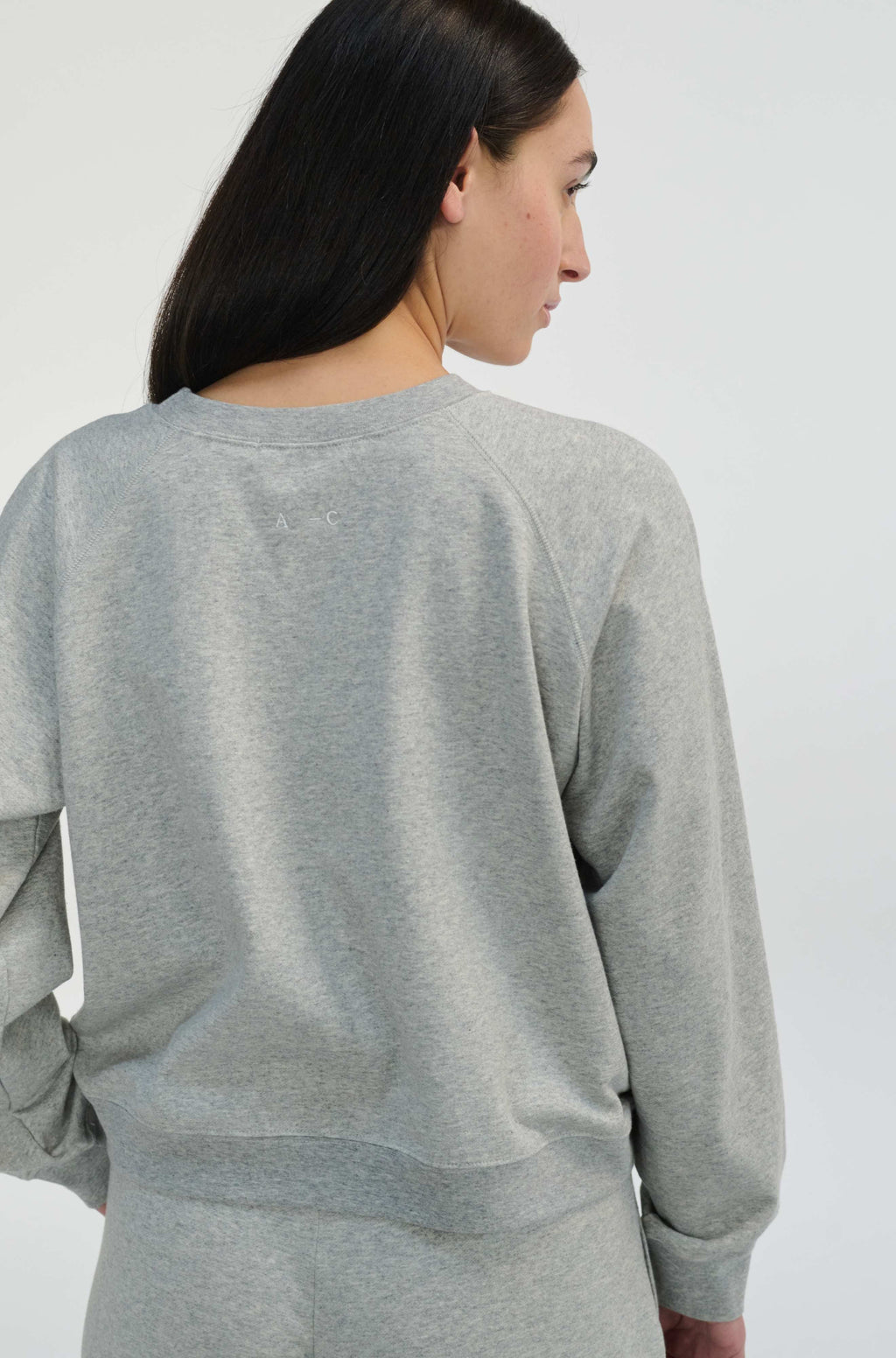 Woman wearing a gray sweatshirt against a white background
