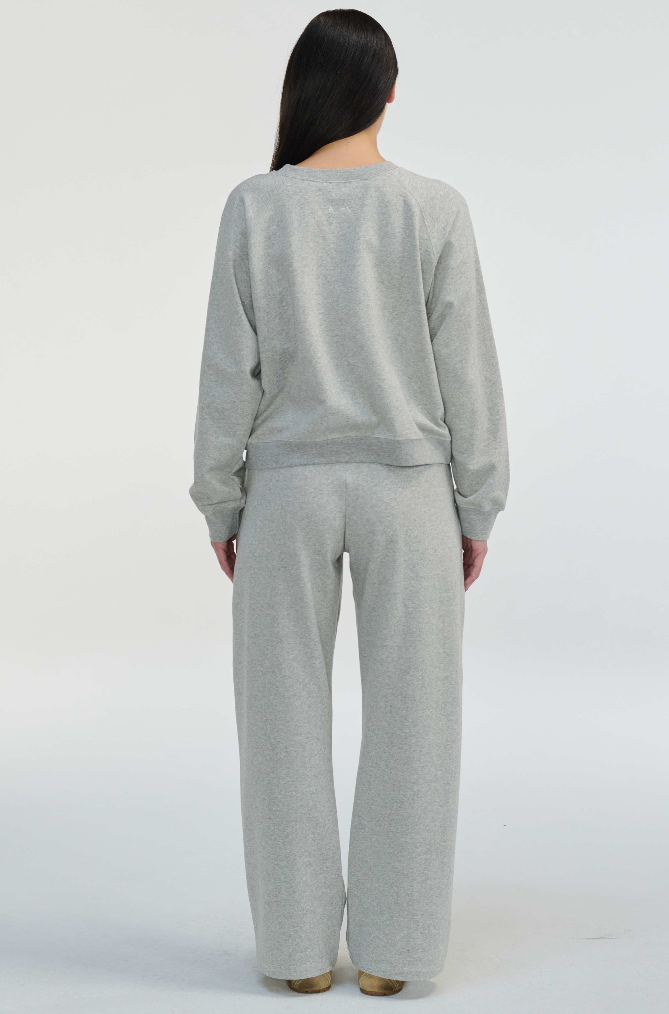 Person wearing a gray sweater and pants set on a white background
