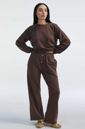 Woman wearing a brown sweatshirt and sweatpants on a white background