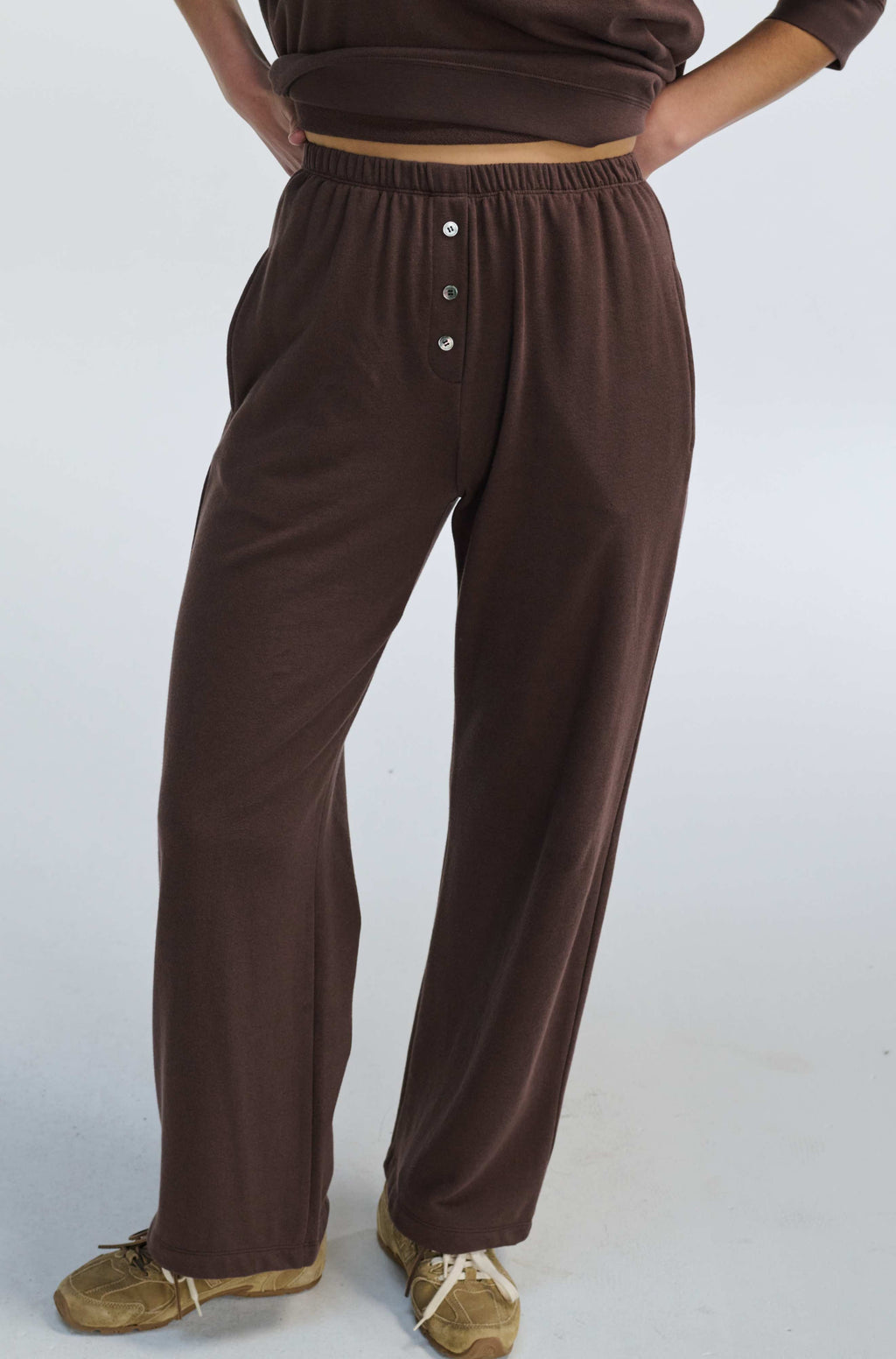 Brown button-up sweatpants worn by a person on a white background