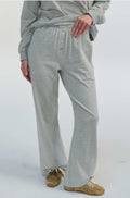 Woman wearing grey sweatpants with buttons up the front on a grey background