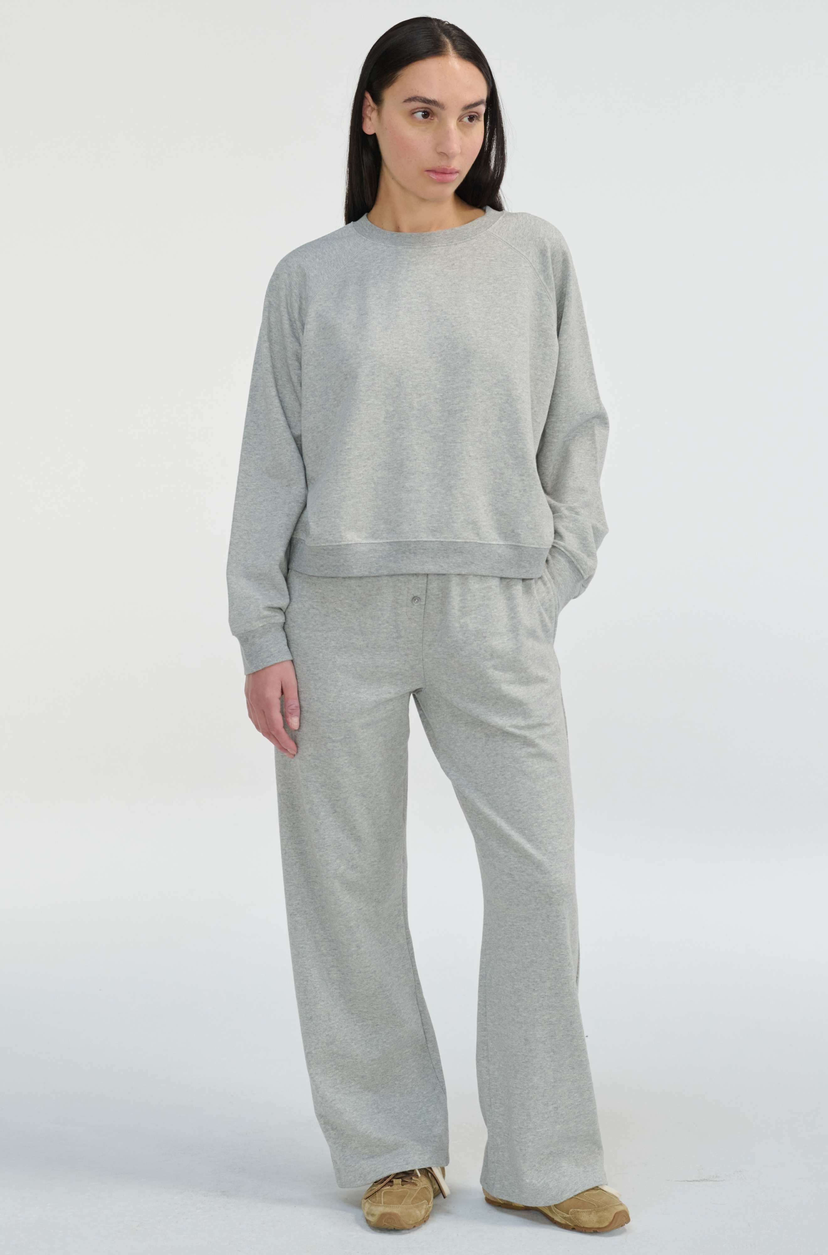 Woman wearing a gray sweatshirt and pants on a white background