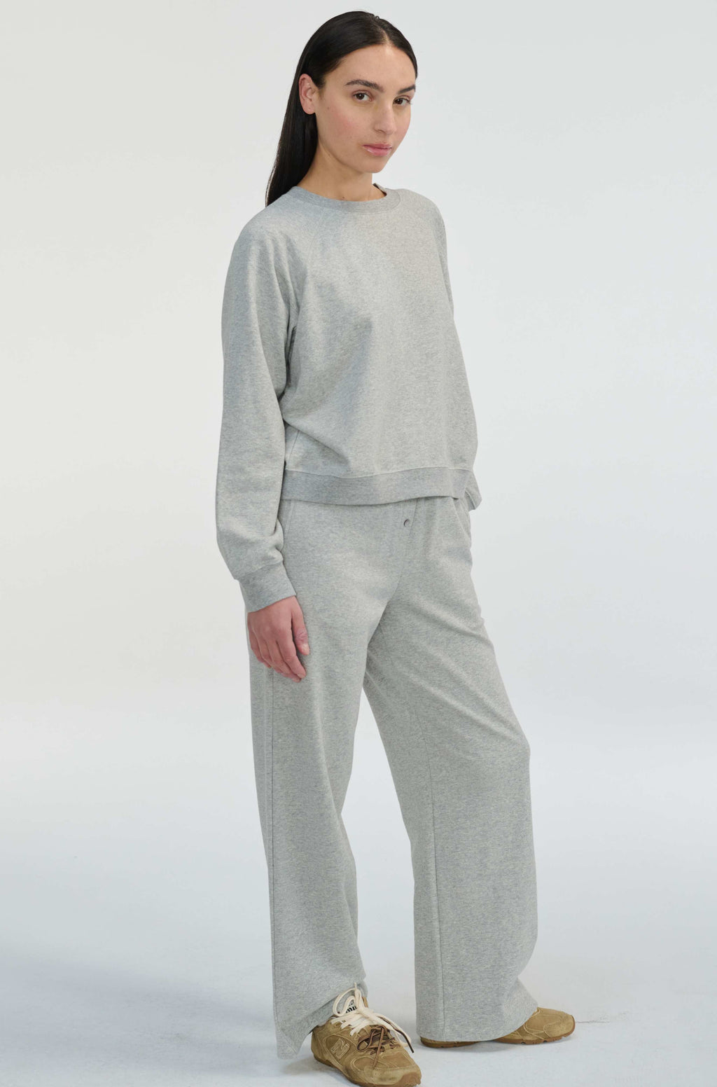 Woman wearing a gray sweatshirt and pants set on a white background