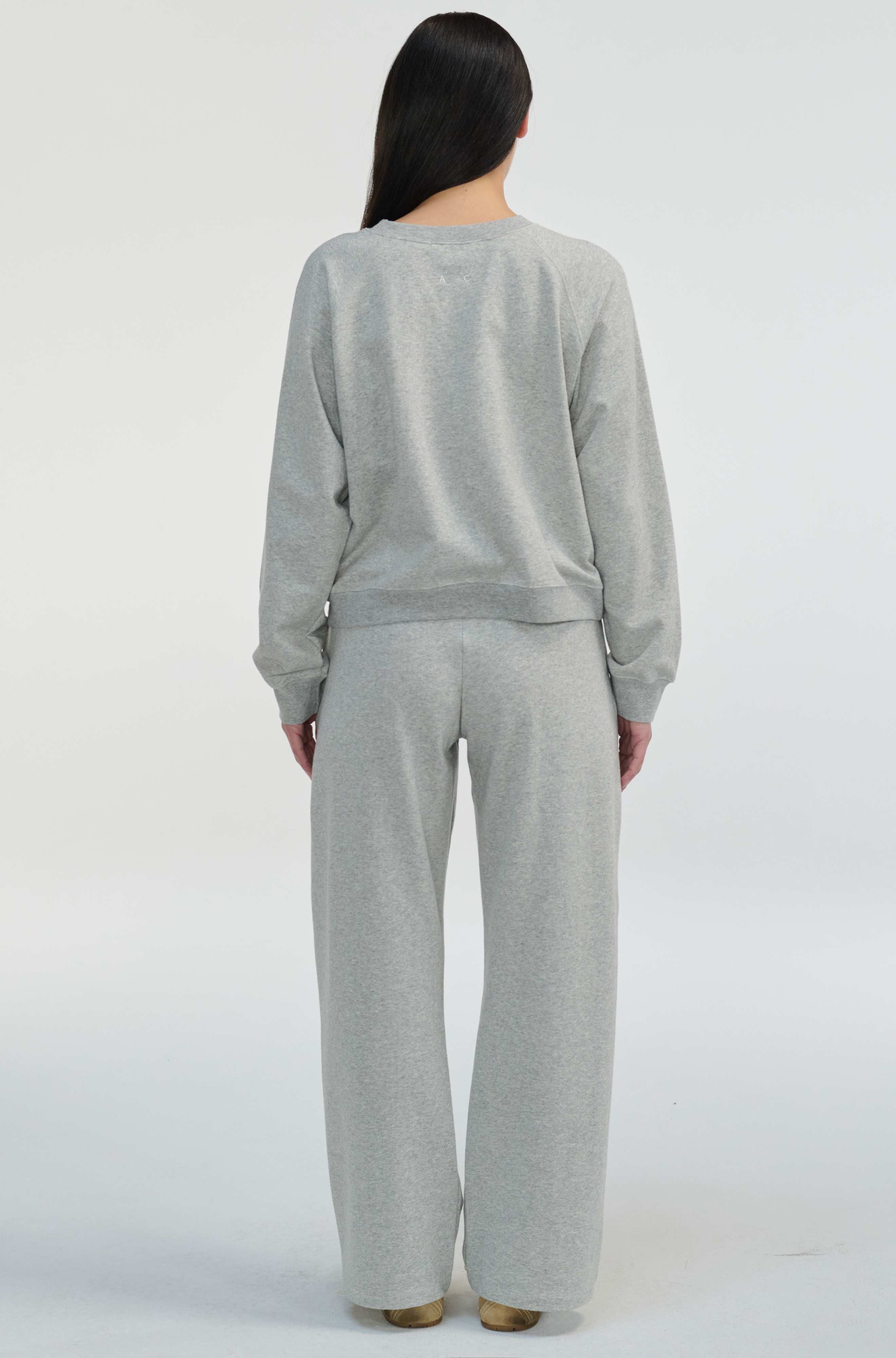 Person wearing a gray sweater and pants set on a white background