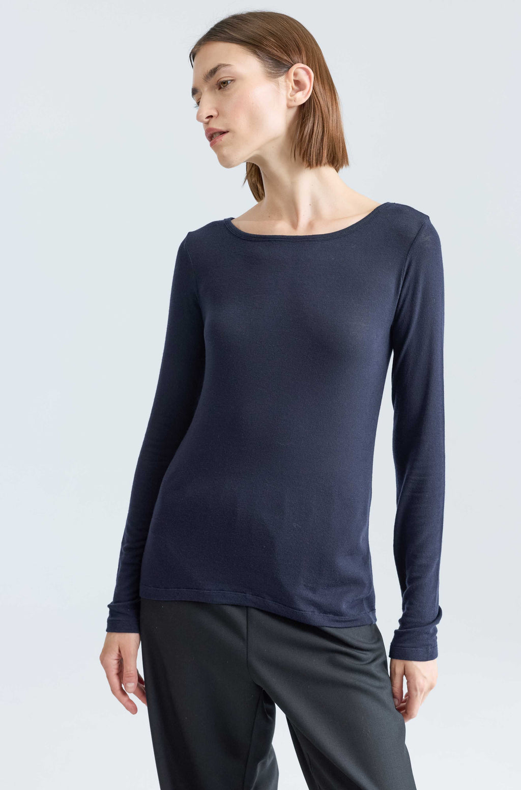 Woman wearing a dark blue long sleeve tee against a light grey background