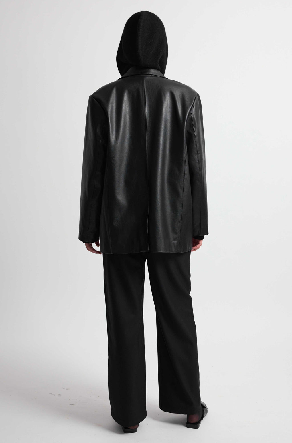 Person wearing a black leather jacket and pants on a white background
