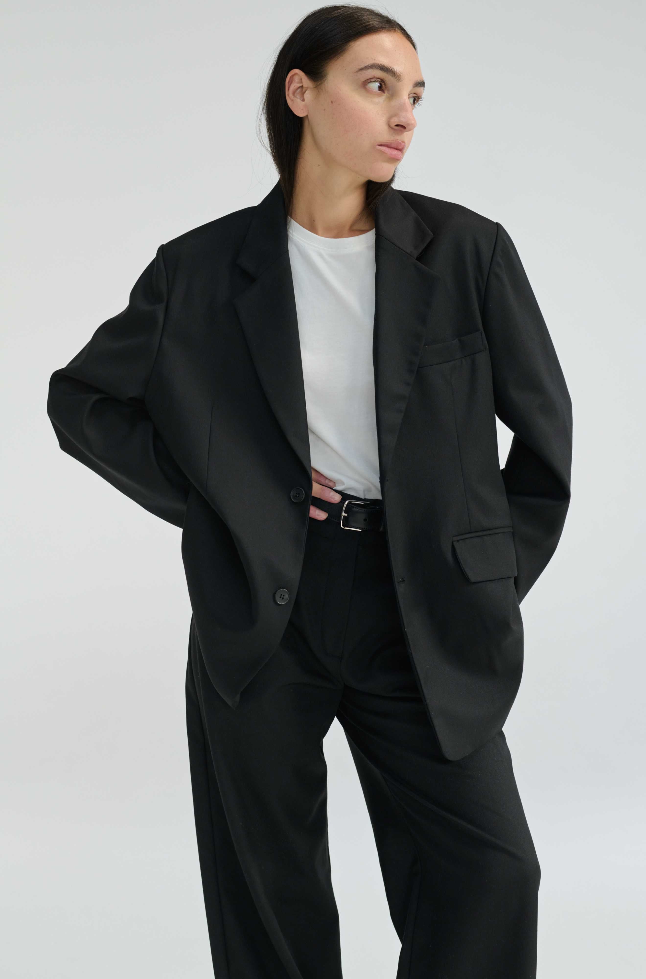 Person wearing a black suit and white shirt on a plain background