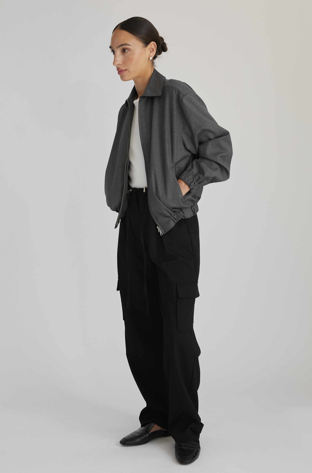 Woman wearing a gray jacket and black pants on a white background