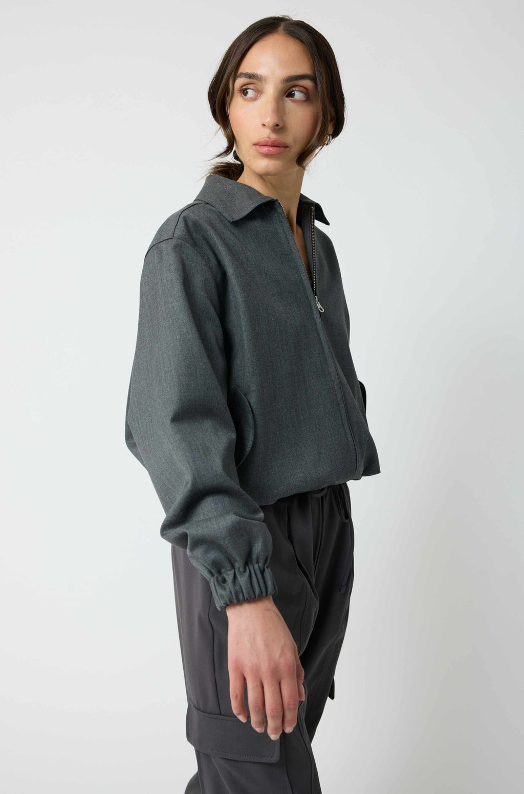 Person wearing a dark gray sweater and pants on a white background