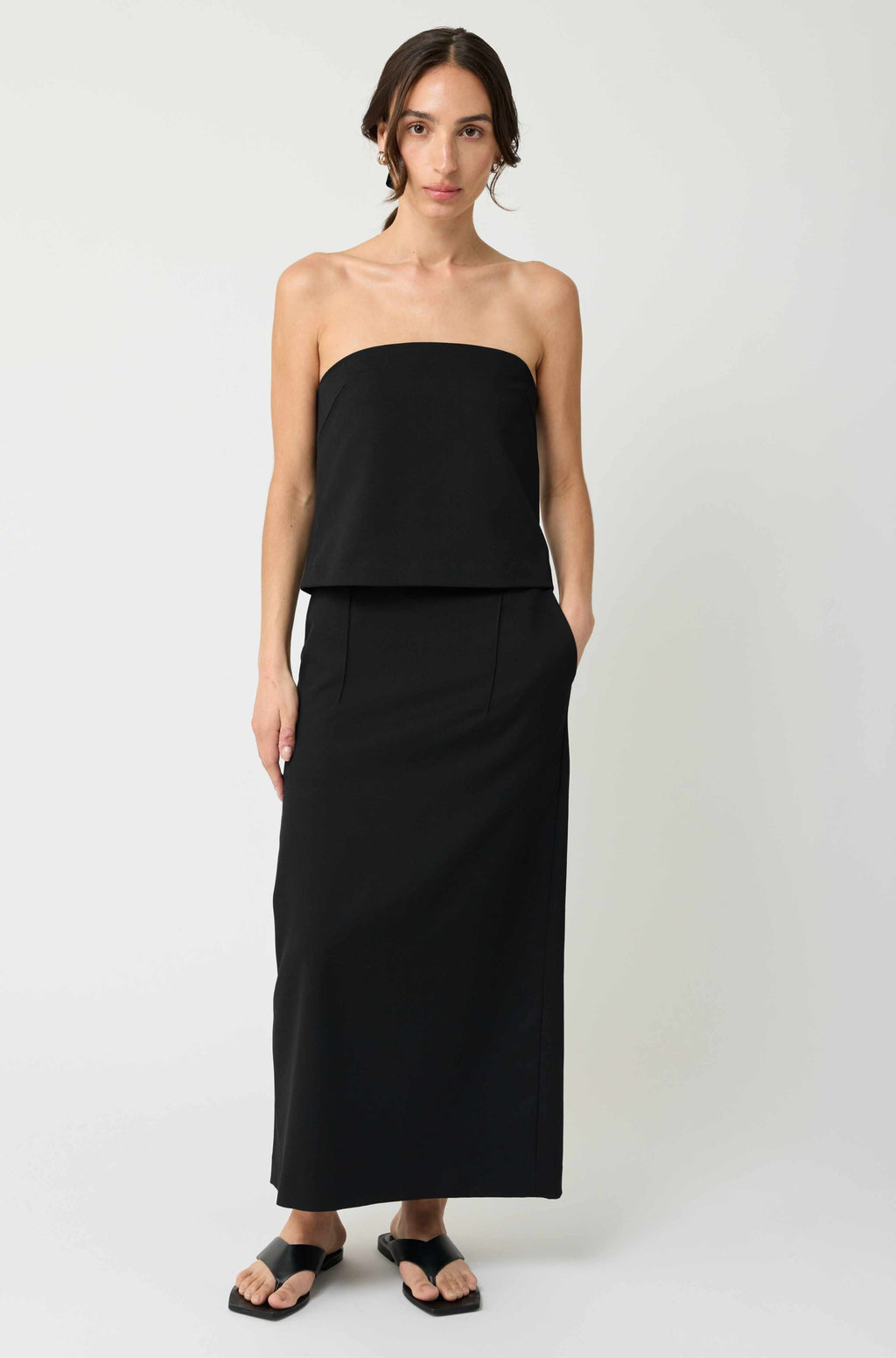 Woman wearing a black strapless top and long skirt on a white background