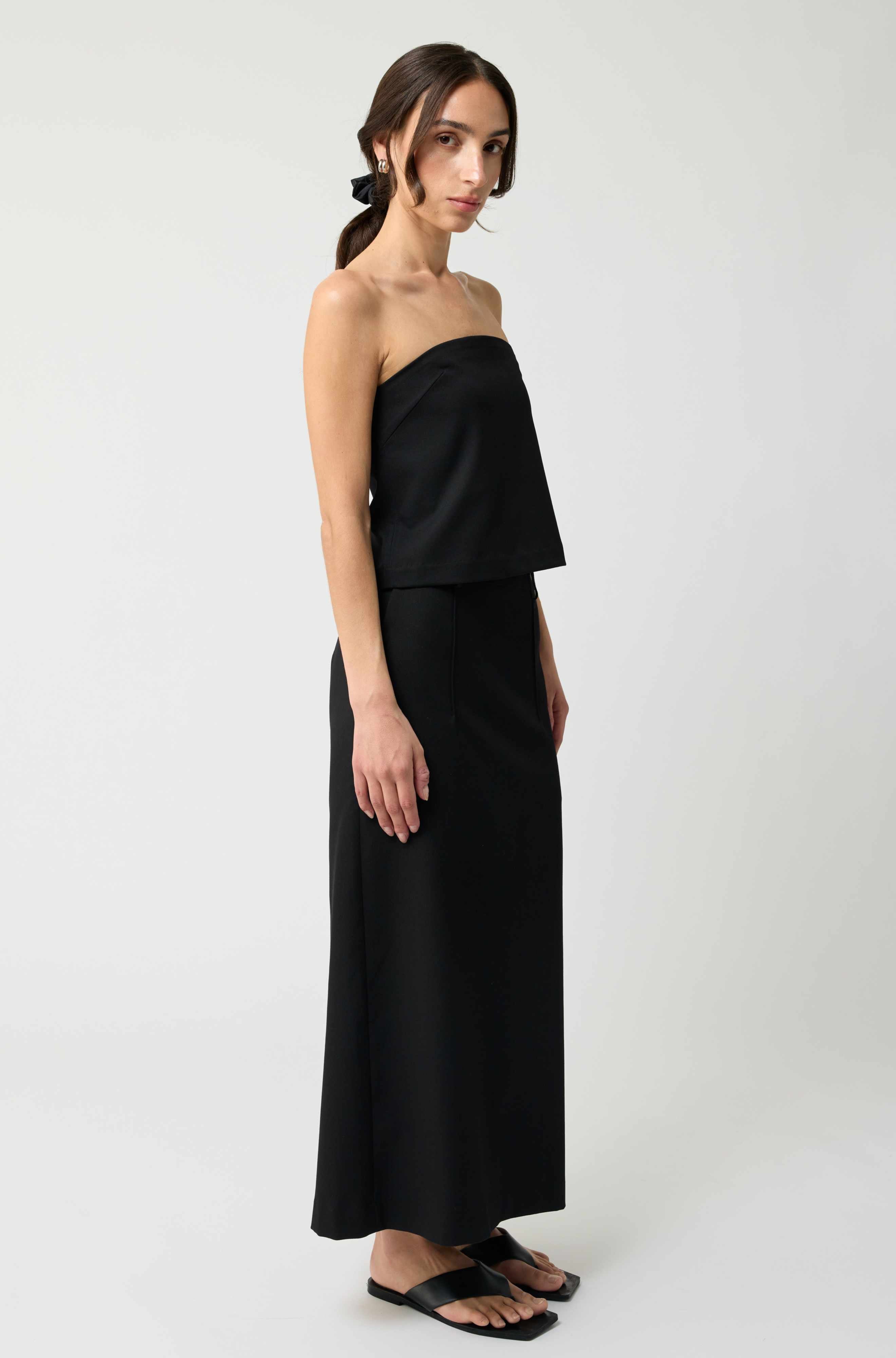 Woman wearing a black strapless dress on a white background